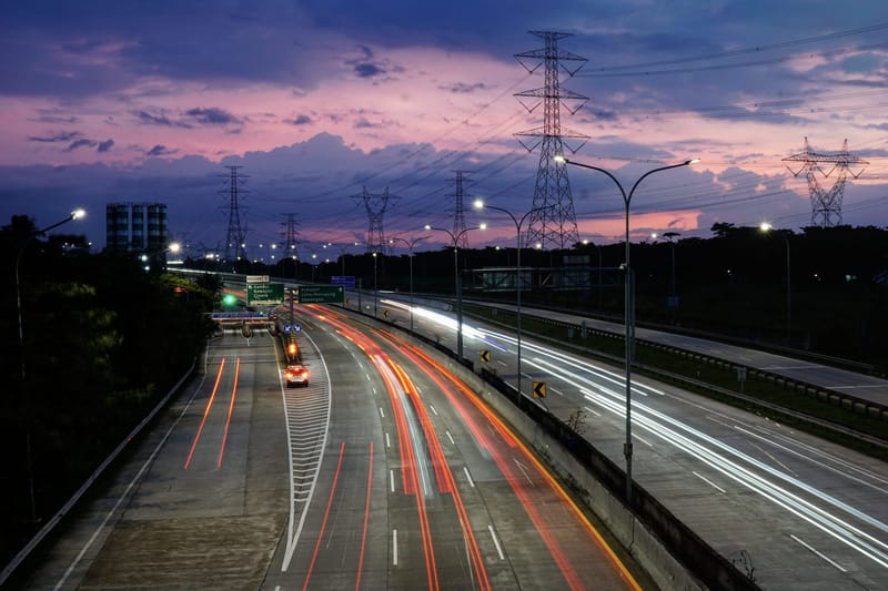 Jalan tol Jakarta saat senja dengan jejak lampu kendaraan.